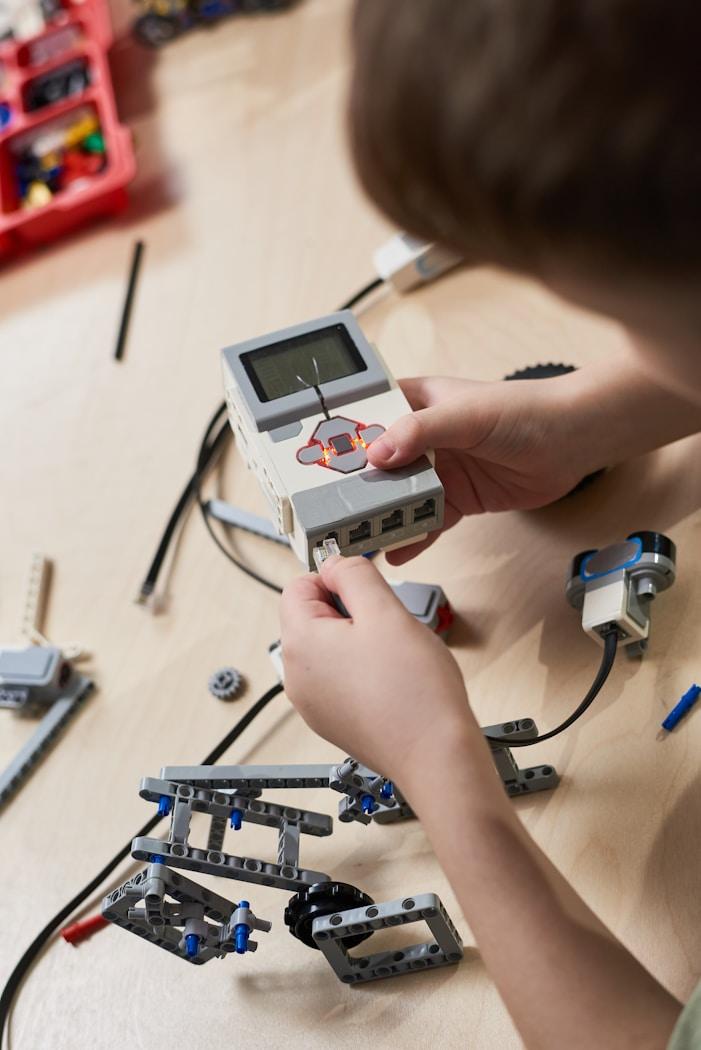 A child wiring a programmable robotics controller at a workbench